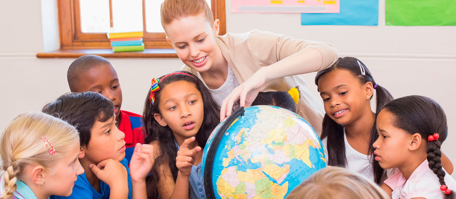 students looking at a Globe with a teacher in classroom