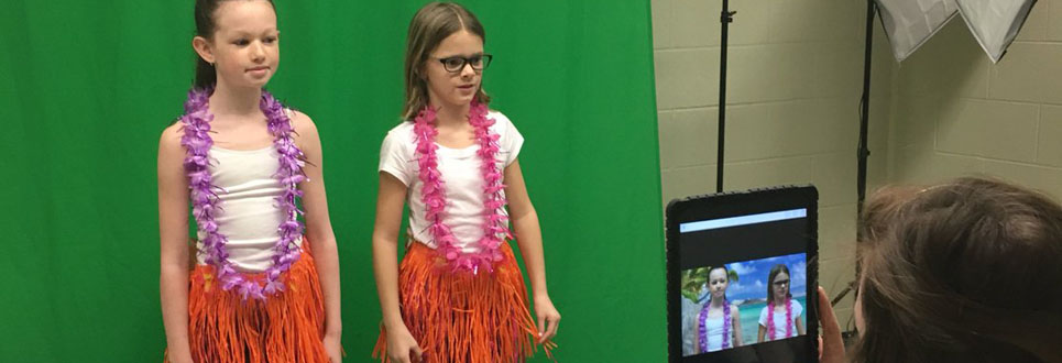 Two female students standing in front of a green screen