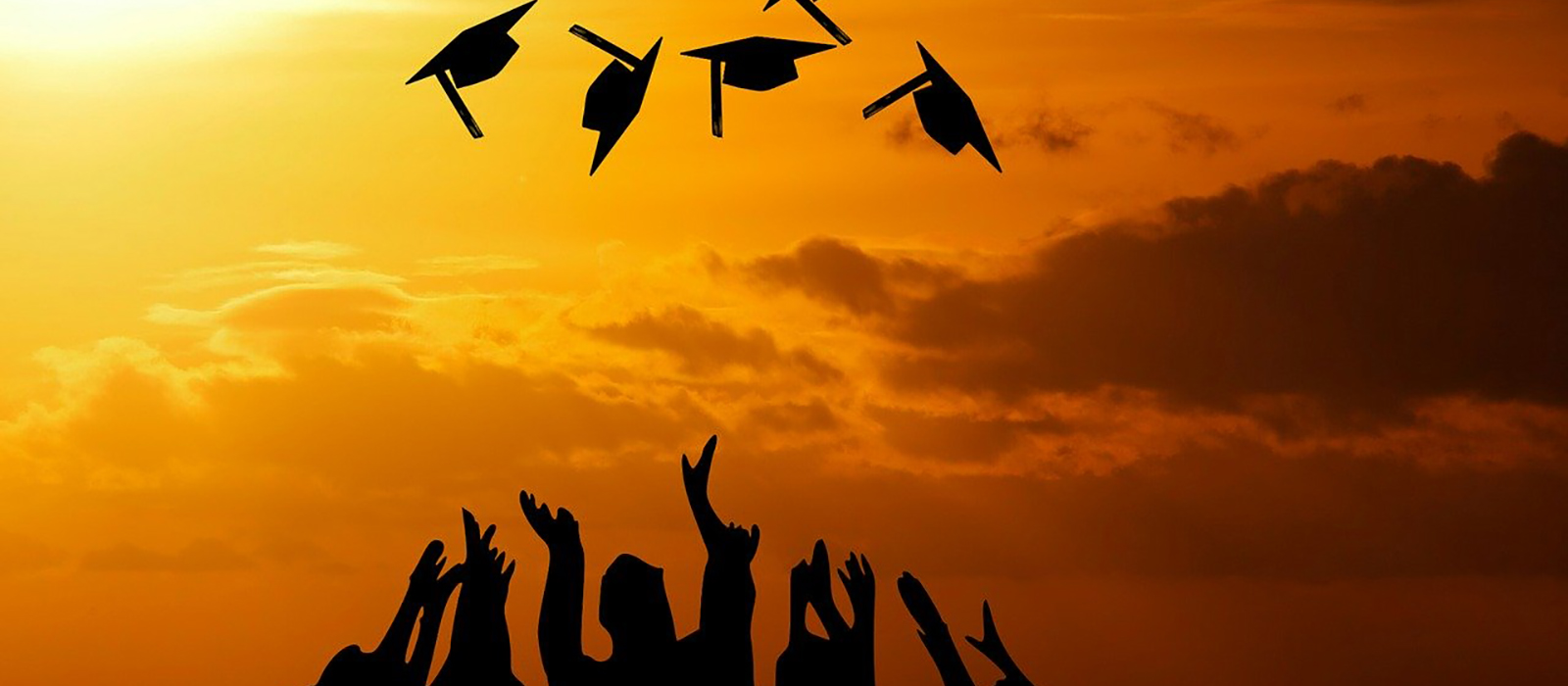 Three female high school graduates in caps and robes.