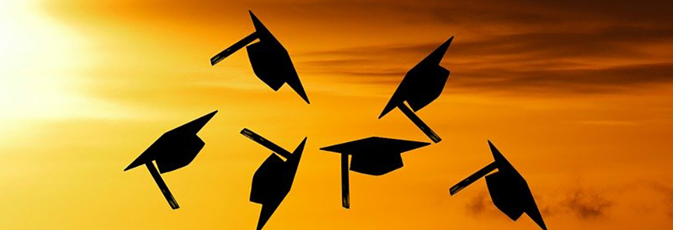 graduation caps in the air outside in the evening