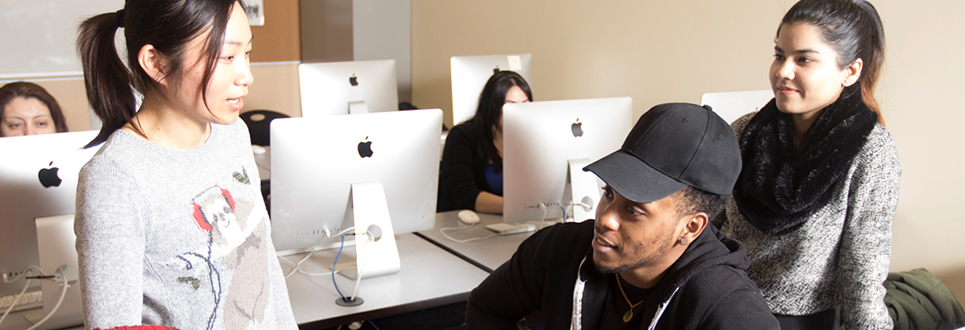 two female and one male student talking by the computers